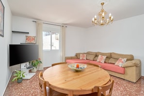 A living room with a round wooden table, beige sofa, and a flat-screen TV.