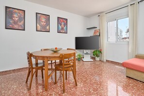 Un'area pranzo con un tavolo rotondo e sedie, una televisione a schermo piatto, un divano e una finestra con tende.