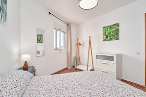 Una camera da letto con un letto, una cassettiera, uno specchio, una finestra con tende e un quadro appeso al muro.