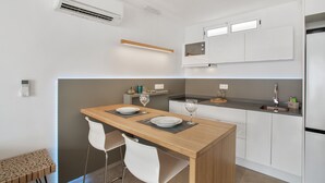 A modern kitchen with a wooden island, white chairs, and a built-in oven. - Vacation Apartment 'Sun and Serenity Pool Wifi' with Sea View, Wi-Fi and Air Conditioning (Puerto Rico)