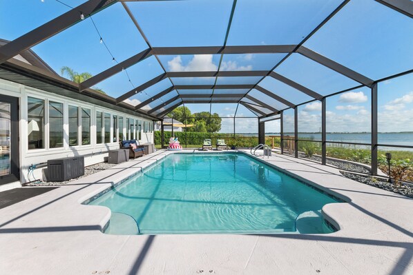 A covered swimming pool with a view of the water body and greenery in the background.