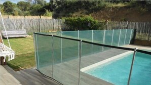 Ein Pool mit Glasveranda und Holzterrasse.