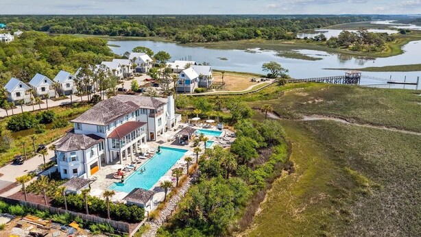 Un gran complejo turístico con varias edificaciones, una piscina y vistas a un lago y vegetación circundante.