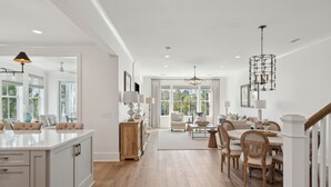 Una cocina amplia con una isla central, pisos de madera y luminarias modernas.