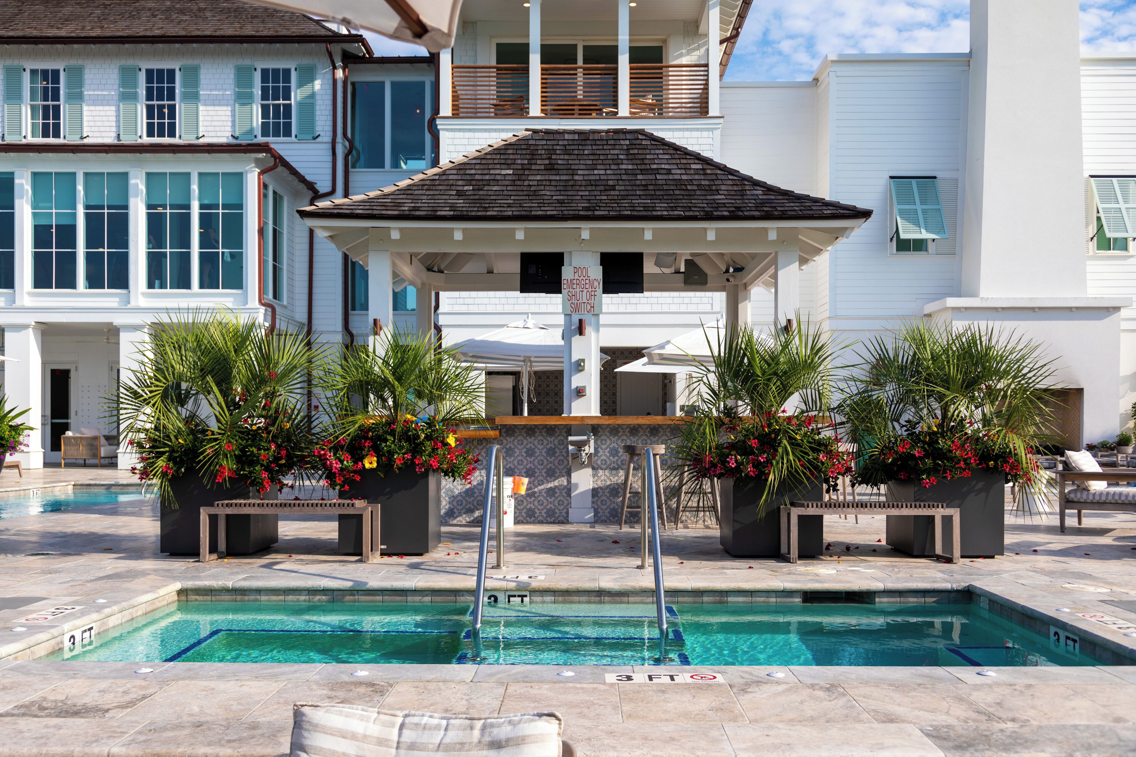 A pool area with two pools, lounge chairs, and a covered seating area.