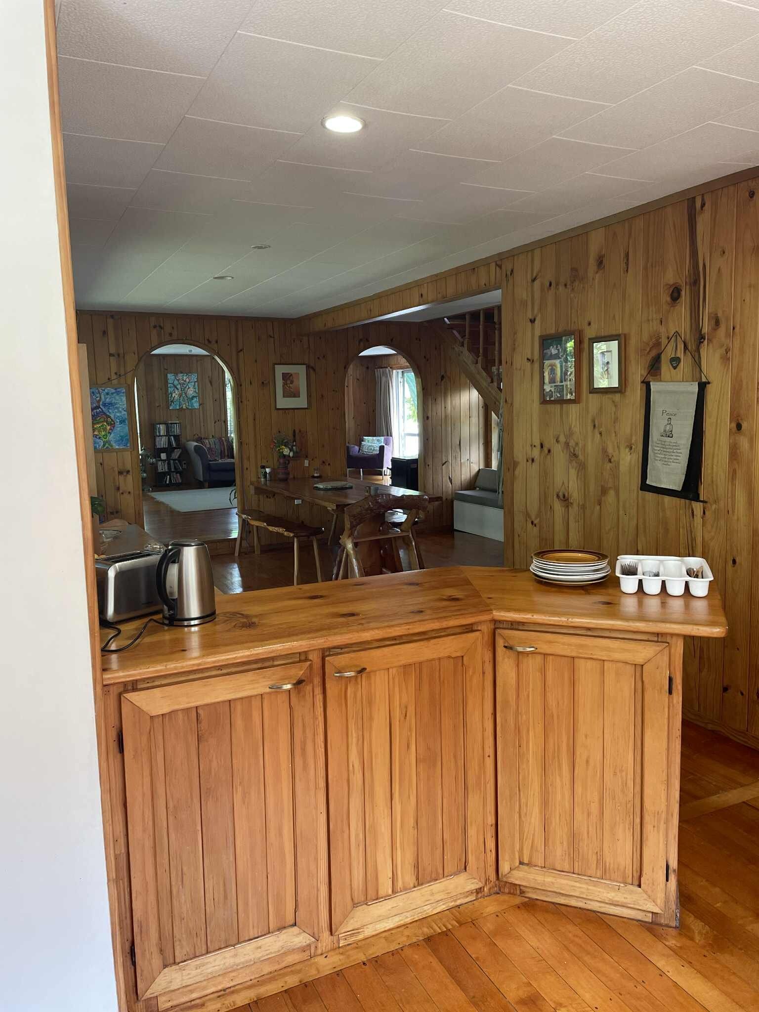 A wooden interior with a kitchen area featuring a wooden counter, cabinets, and a toaster.