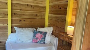 Een houten kamer met een bed, een nachtkastje en een lamp.