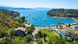 Un pueblo costero con un puerto deportivo, casas y un paisaje montañoso.