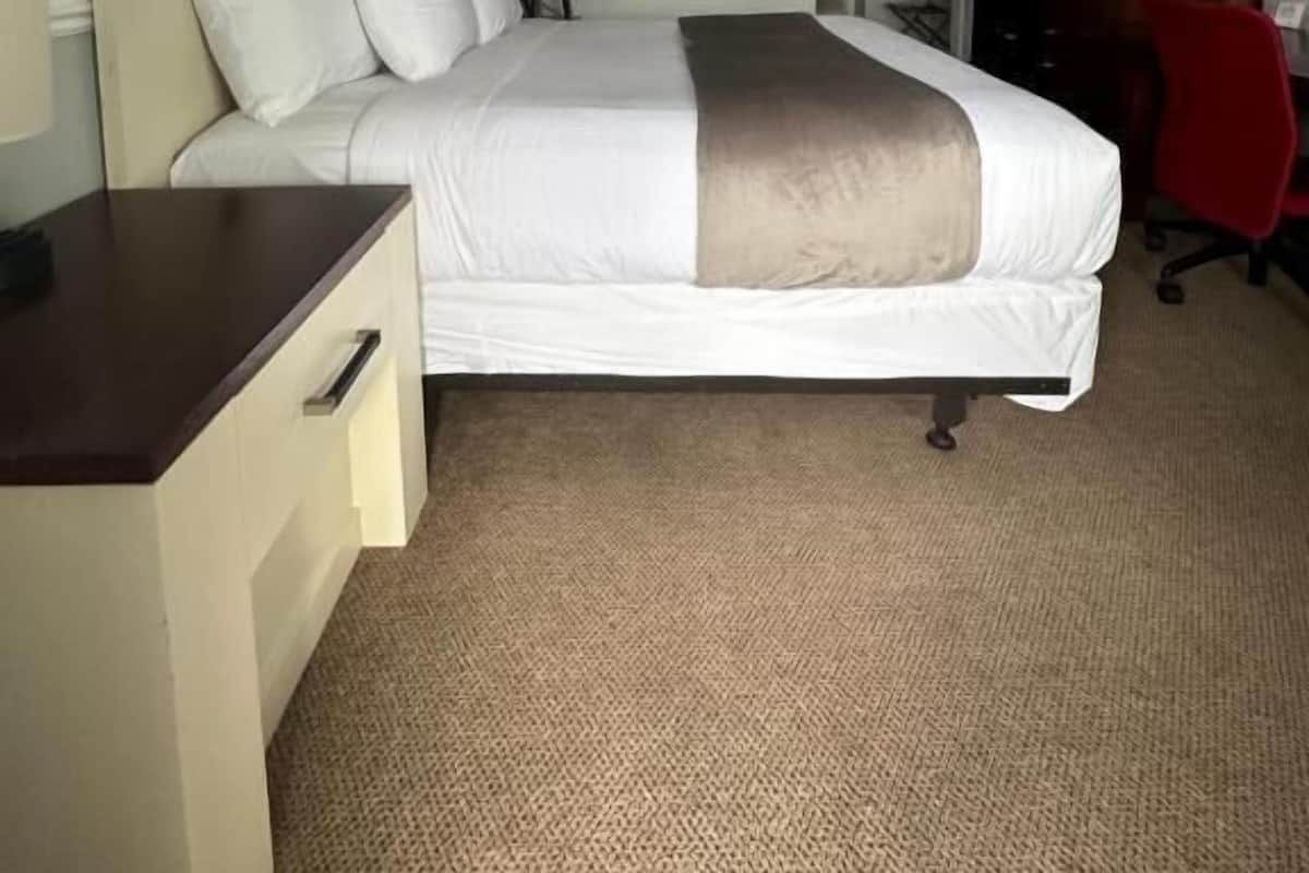 Una habitación de hotel con una cama, un escritorio, una silla, un televisor y una silla de oficina roja.