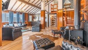 A spacious living area with leather sofas, a large chandelier, and a wood-burning stove. - Sierra Nevada Mountains Apartment ‘Edificio Los Alayos’ (Sierra Nevada)