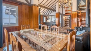 A dining area with a glass table, wooden chairs, and a chandelier. - Sierra Nevada Mountains Apartment ‘Edificio Los Alayos’ (Sierra Nevada)