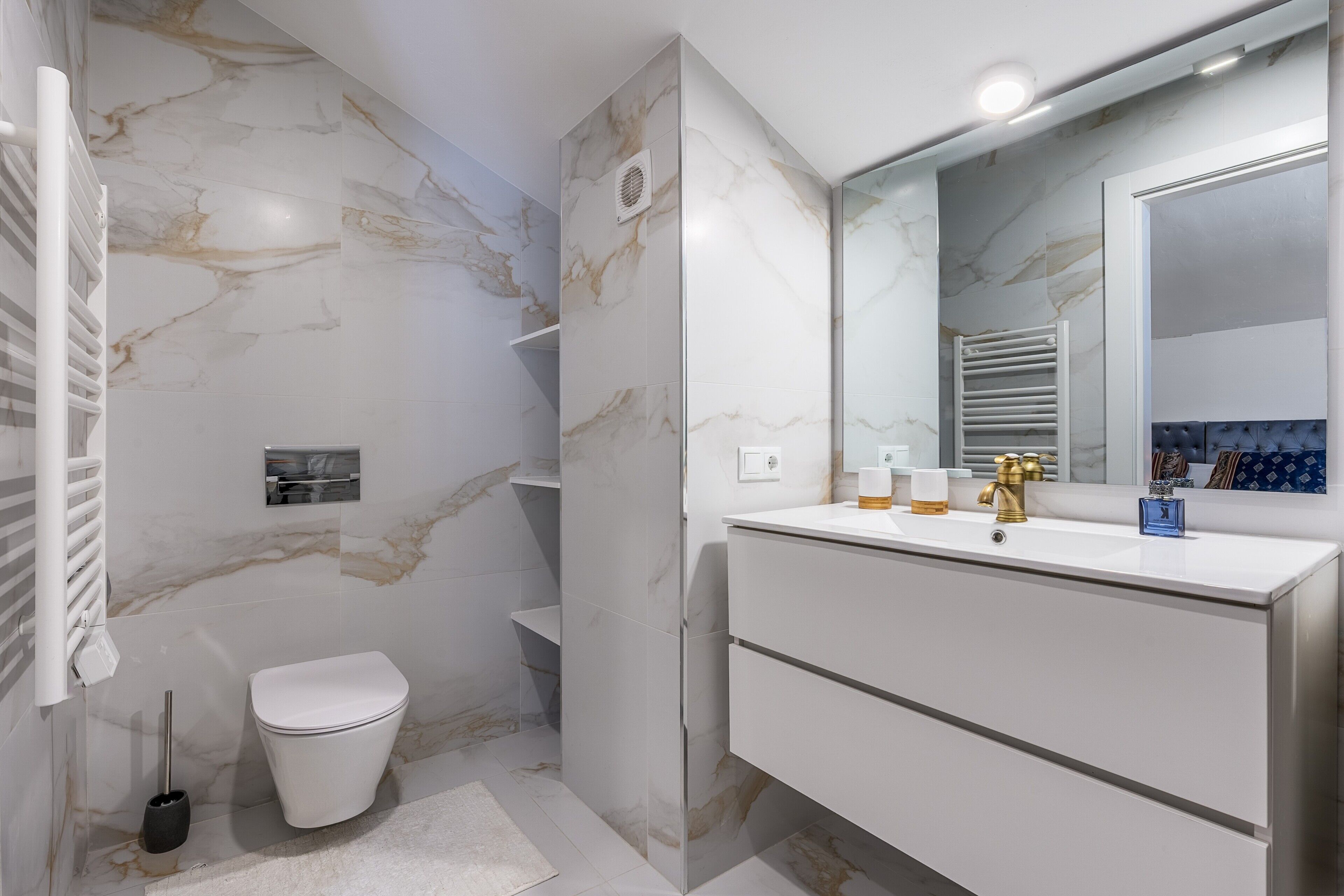 Un baño con inodoro, lavamanos con espejo y zona de ducha.
