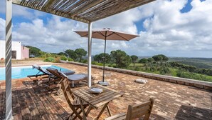 Una terraza en la azotea con piscina, sillones de descanso y una mesa con sombrilla.
