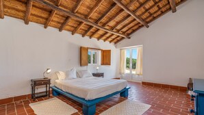 Un dormitorio con cama, mesita de noche y ventana con cortinas.