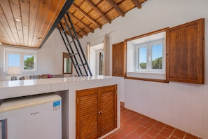 A kitchen with a wooden ceiling, a refrigerator, a window, and a door. - Holiday Home 'Lua' with Sea View, Shared Pool and Wi-Fi (Aljezur)