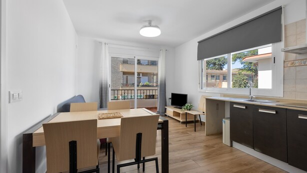 Una cocina moderna con comedor, televisor y ventana con vista a un edificio.