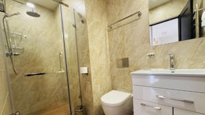 A modern bathroom with a glass-enclosed shower, a white toilet, and a vanity with drawers.