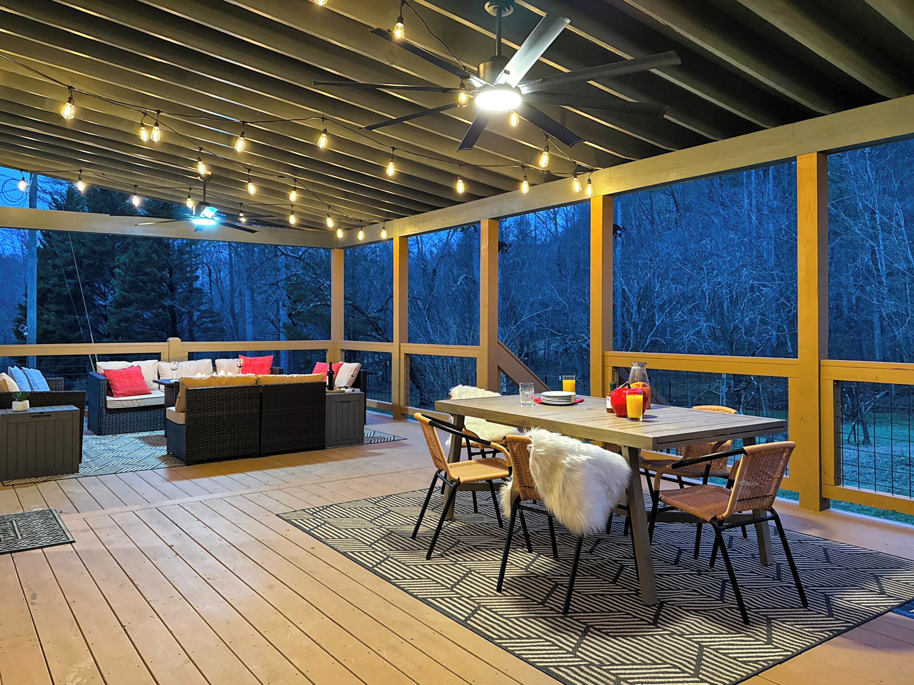 A covered outdoor area with a dining table, chairs, and a sofa.