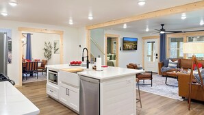 Une cuisine moderne dotée d’un îlot central, d’un plancher en bois et d’un coin repas avec une table et des chaises.