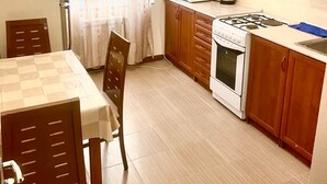 Une cuisine compacte dotée de meubles en bois, d’un four à micro-ondes, d’une cuisinière et d’une table à manger avec des chaises.