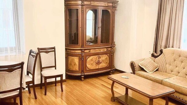 Un salon avec un plancher en bois, un canapé, une table basse, un meuble et un lustre.