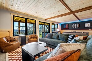 Een moderne woonkamer met een grote bank, een plufkussen, een salontafel en een open haard.