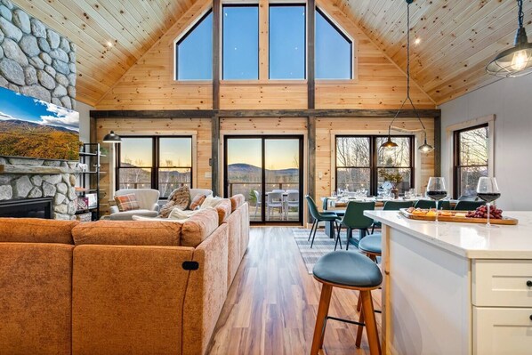 A spacious living area with a large sofa, a dining table with chairs, and a kitchen area with a bar.