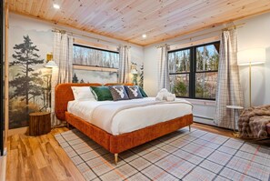 A bedroom with a wooden ceiling, a bed with white bedding, plaid curtains, and a forest mural on the wall. - Sleep 29! Pano Views, Hot Tubs, Saunas, Game Rooms, Fire Pits, Dogs OK (Bethel)