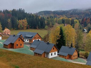 A cluster of wooden cabins with sloped roofs, surrounded by a forested landscape. - Vacation home Adélka by Interhome (Smržovka)