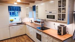 A kitchen with white cabinets, a wooden countertop, a built-in oven, a microwave, and a coffee machine. - Vacation home Adélka by Interhome (Smržovka)