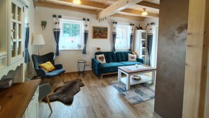 A cozy living room with wooden beams, a blue sofa, a small table, and a rug. - Vacation home Adélka by Interhome (Smržovka)