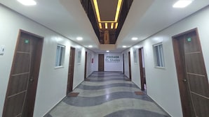 A hotel corridor with a modern design, featuring a patterned floor, wooden doors, and a sign reading "Pousada EL Shaday". - Pousada Elshaday (Vitória da Conquista)