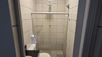 Ein kleines Badezimmer mit Fliesen, Toilette, Waschbecken und Dusche.
