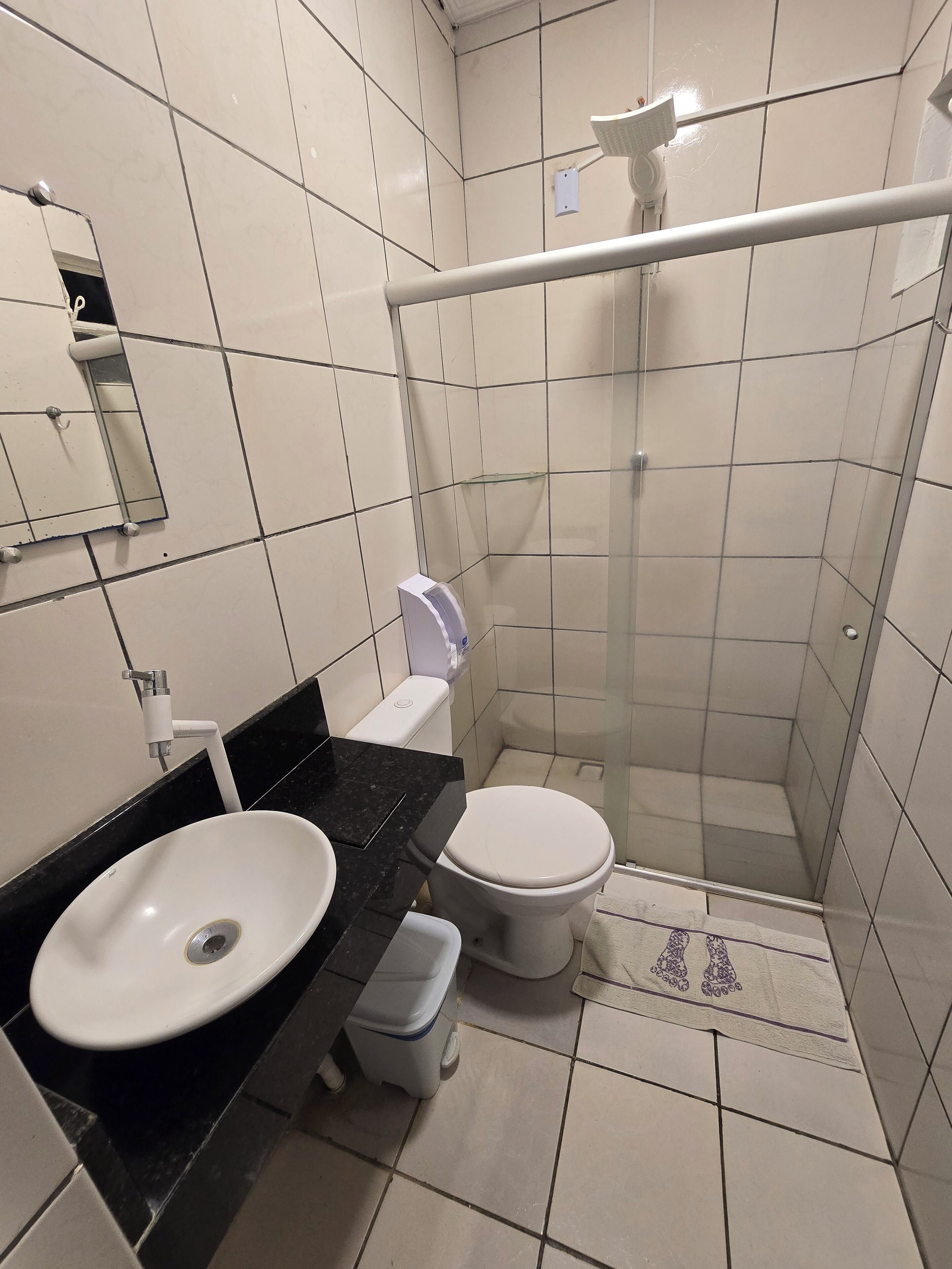 A compact bathroom with a white sink, toilet, and glass-enclosed shower.