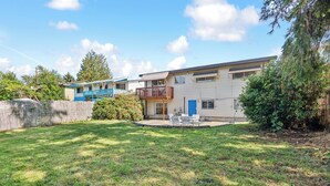 A residential area with a house featuring a balcony, a fenced yard, and a clear sky. - Brighton Retreat - Walk to Metro (Seattle)