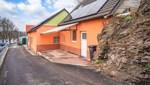 Un edificio residencial con techo inclinado, paneles solares y un camino de entrada pavimentado.