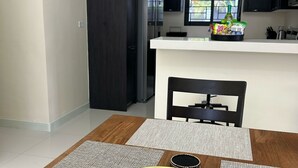 A modern kitchen with dark cabinets, a white countertop, and a dining area with a table and chairs. - Sunset Rose Retreat – 2BR Private Villa in Ocho Rios with 24-Hour Security (Ocho Rios)