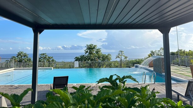 A pool area with a view of the ocean, a covered seating area, and a signboard. - Sunset Rose Retreat – 2BR Private Villa in Ocho Rios with 24-Hour Security (Ocho Rios)