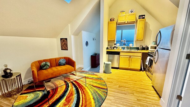 A modern kitchen with yellow cabinets, a stainless steel refrigerator, and a microwave. - The Retro Carriage House (Denver)
