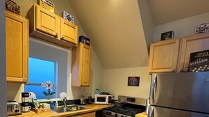 A modern kitchen with wooden cabinets, stainless steel appliances, and a window providing natural light. - The Retro Carriage House (Denver)