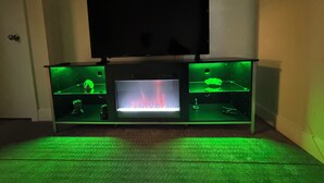 A room with a TV mounted on a cabinet, a small aquarium, and a fireplace. - The Retro Carriage House (Denver)