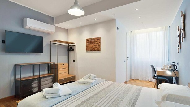 Een moderne hotelkamer met een bed, bureau, stoel, televisie en kledingkast.