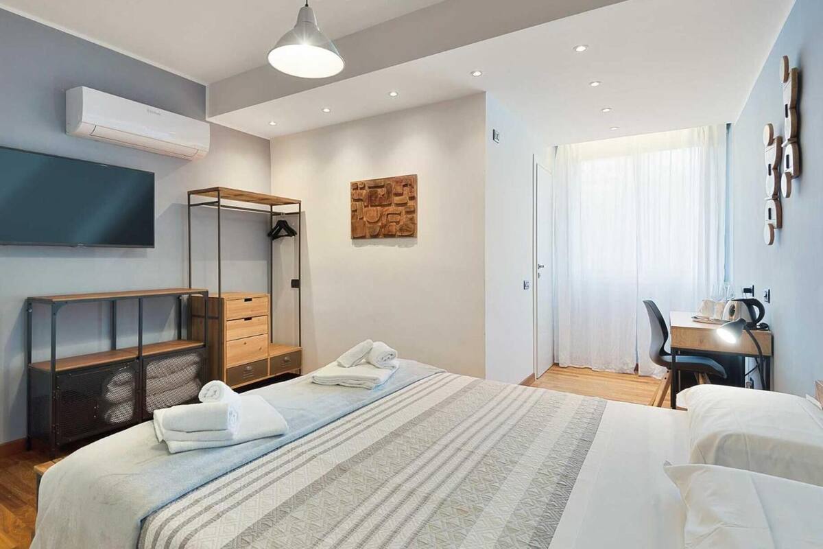 Une chambre d’hôtel moderne équipée d’un lit, d’un bureau, d’une chaise, d’une télévision et d’une armoire.