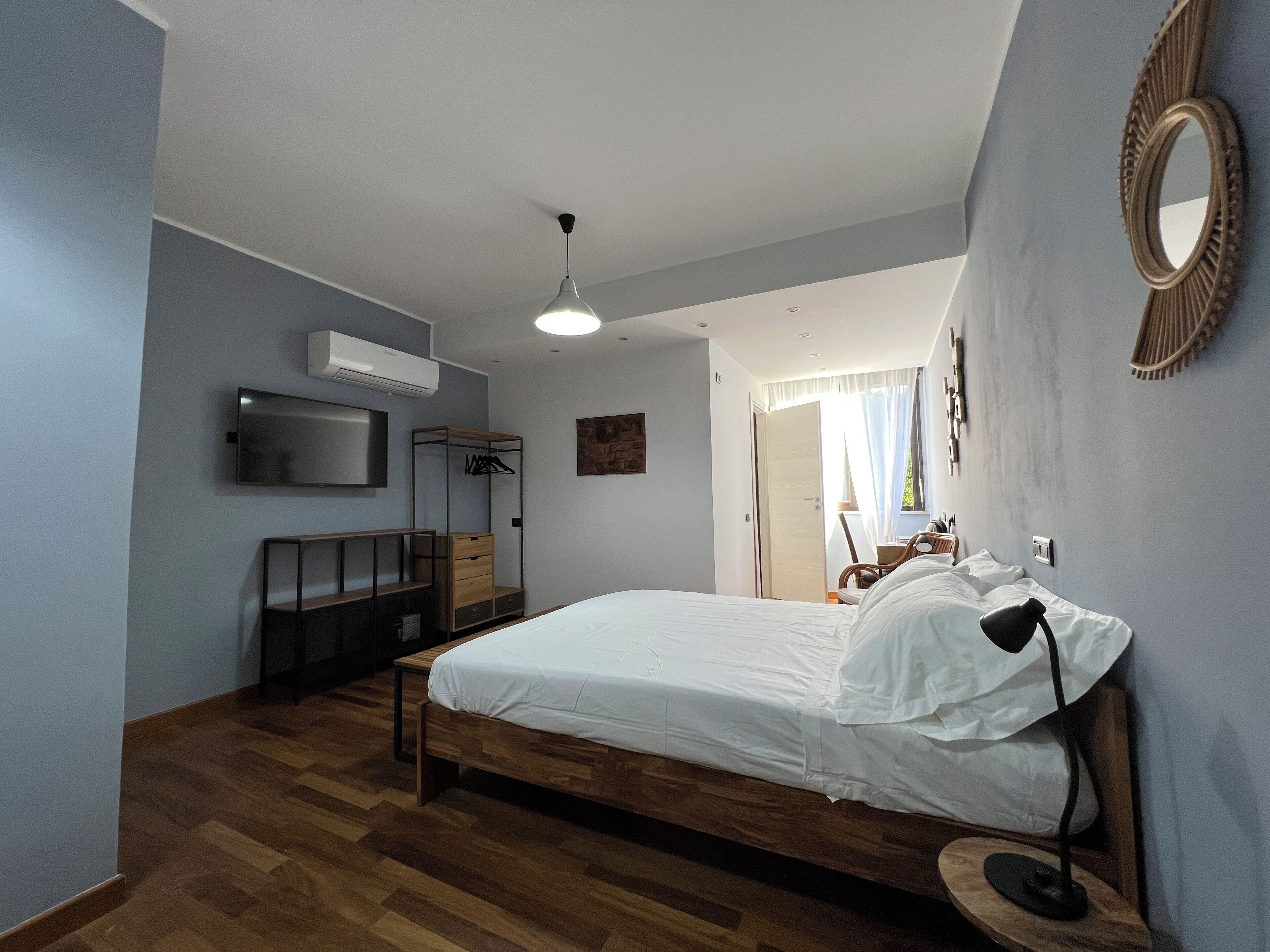 Un dormitorio con cama de madera, televisión montada en la pared, armario y ventilador de techo.