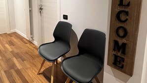 Een gang met twee zwarte stoelen en een 'WELCOME'-bord aan de muur.
