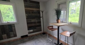 A room with a modern design, featuring a wooden wall panel, a small table with two chairs, a potted plant, and a floor lamp. - 3-bedroom hillside property in woods with fireplace and lake view (Lemont)