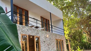 A modern two-story house with a stone facade, large windows, and a balcony. - Earth bomb Susurros del Mar Cabin (Bolívar)