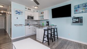Une cuisine moderne avec des meubles blancs, un plan de travail en granit et un tabouret de bar noir.