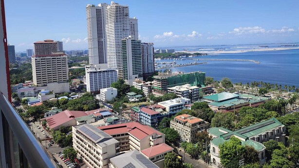 A coastal cityscape with high-rise buildings, a marina, and a beach. - 1-bedroom condo with a magnificent Manila Bay sunset view. (Manila)