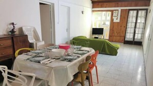 A dining area with a table set for four, surrounded by chairs, and a green sofa in the background. - Entire 2-bedroom townhouse (Saint-Denis)